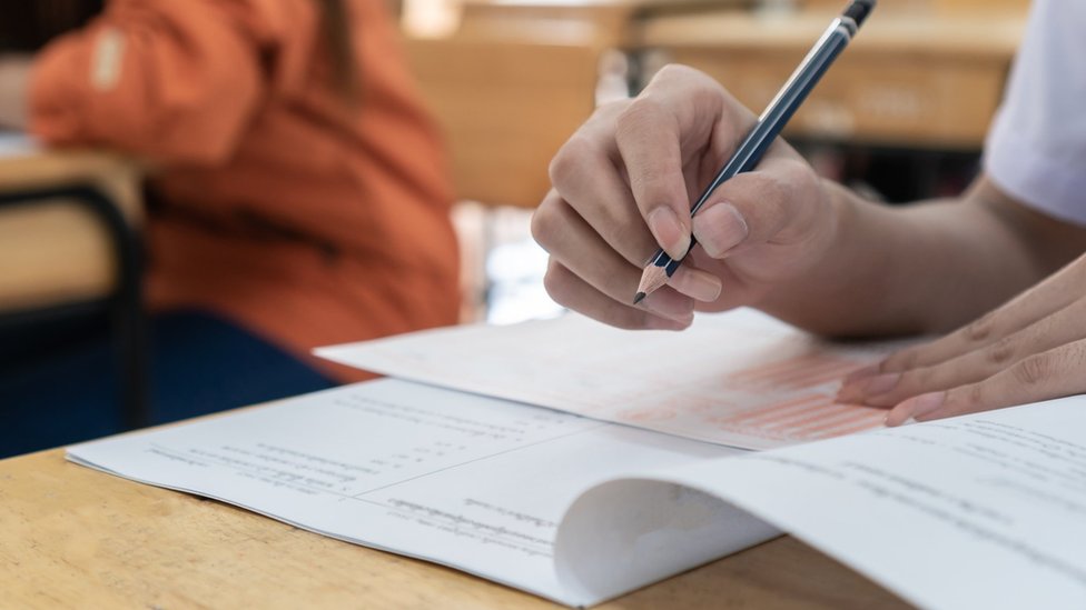 A close up of a student holding a pencil in the middle of an exam