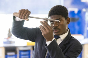 A male student is seen wearing his academy uniform whilst concentrating on an activity in Design & Technology.
