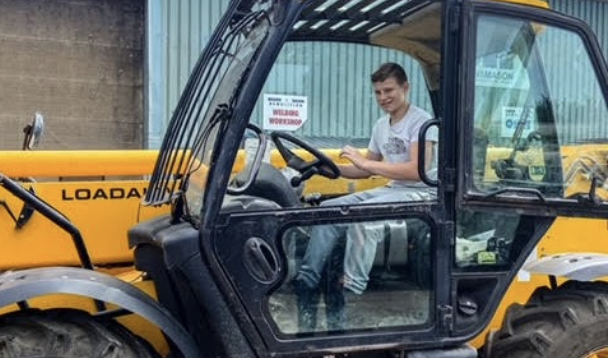 A male Leigh Academy student can be seen smiling for the camera, whilst in the driver's seat of a construction vehicle.