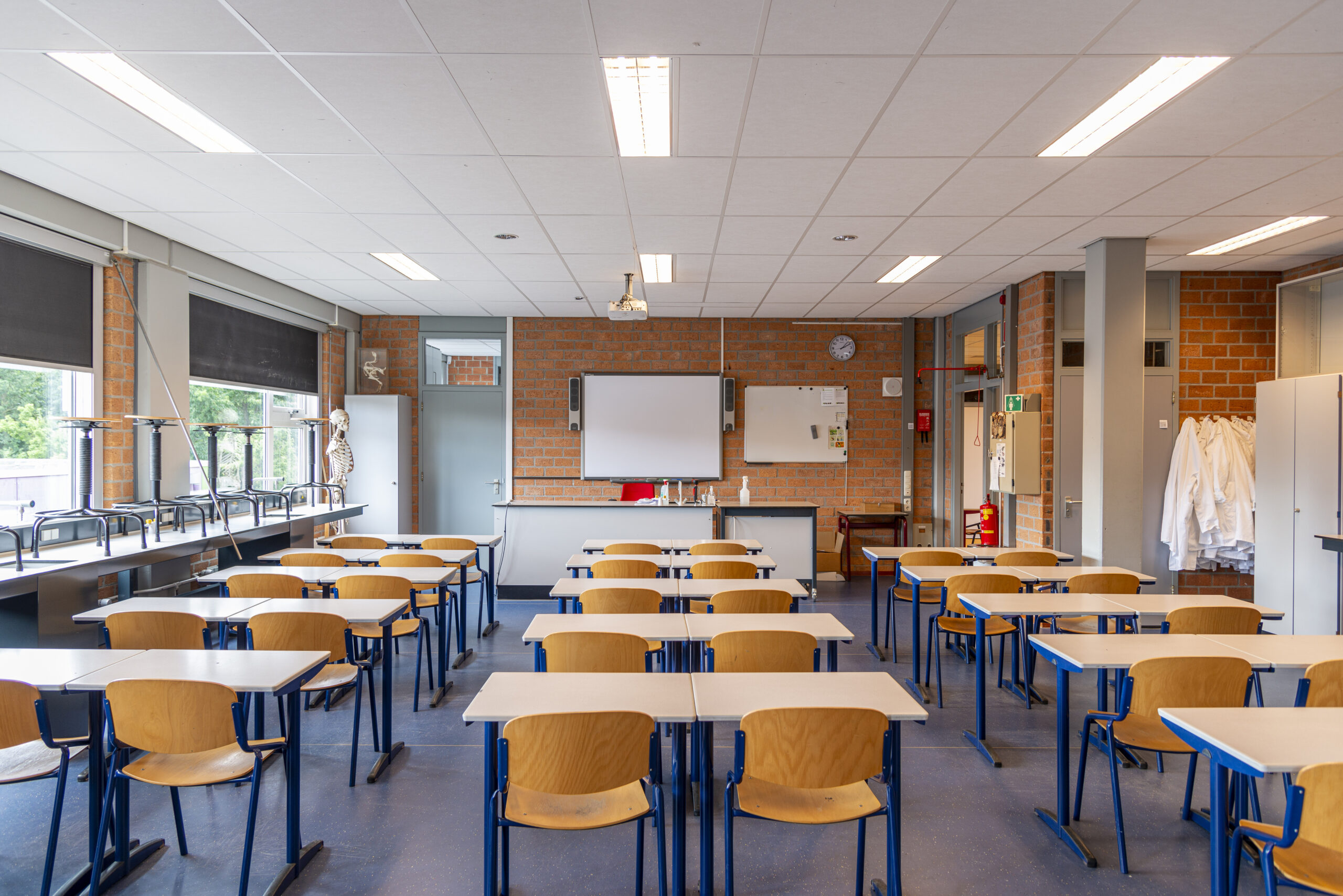 A photo looking at an empty classroom with tables and chairs in it.